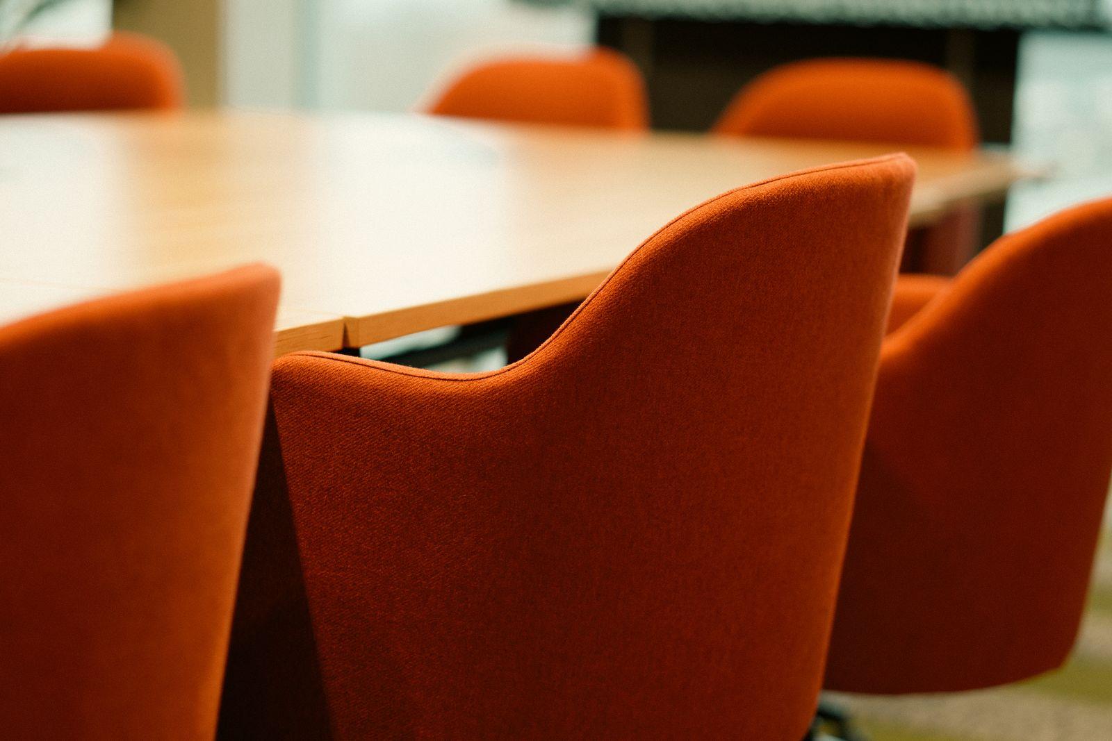 Empty boardroom with orange chairs around a long table