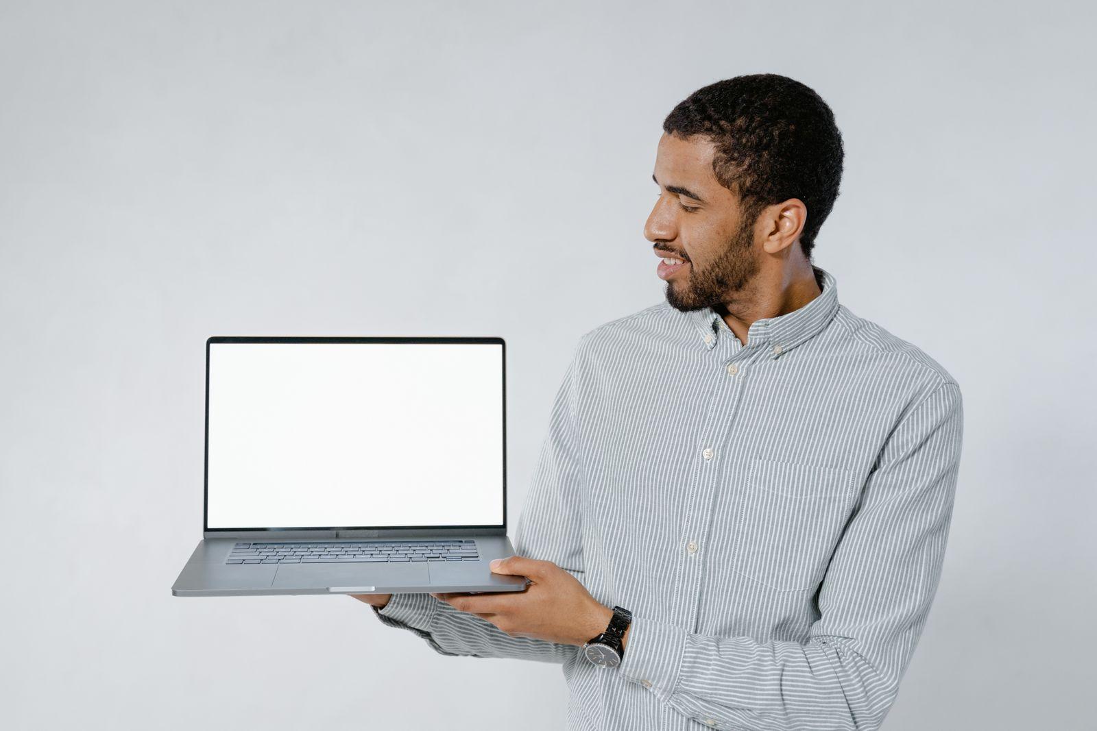 Man holding an open laptop with a blank screen
