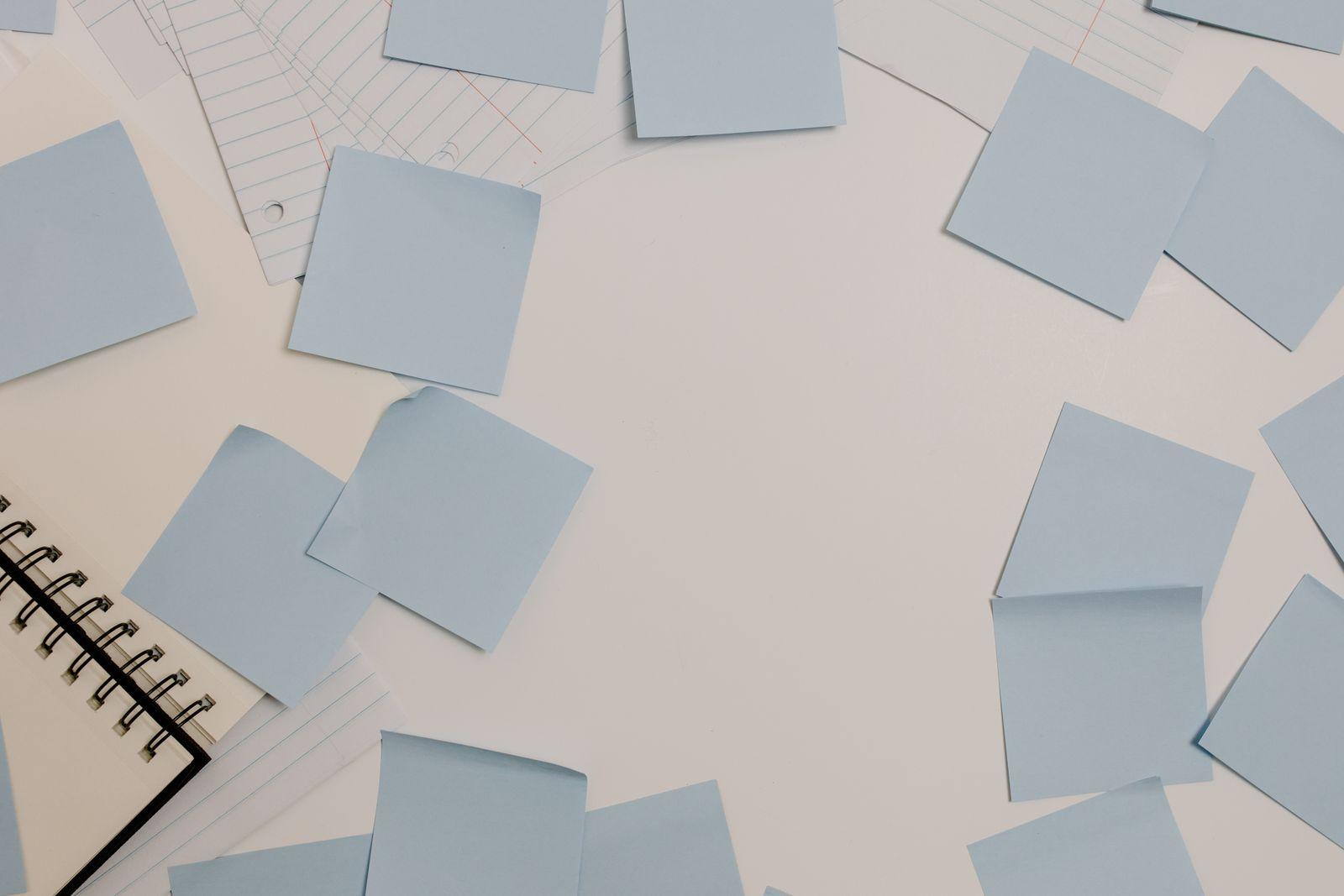Blank blue sticky notes scattered around a spiral notebook