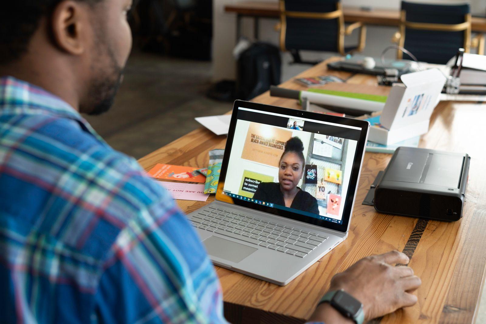 Person on a video call with a colleague shown on a laptop screen