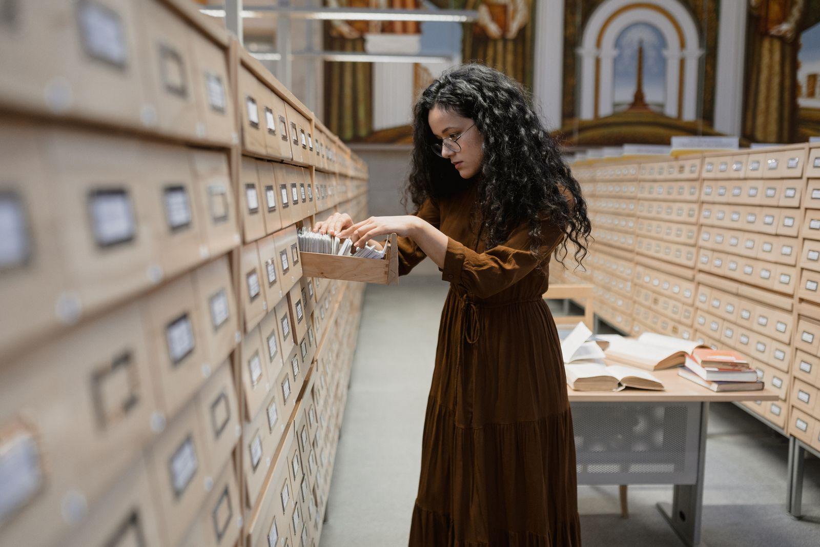 Woman searching card catalog drawers in an archive