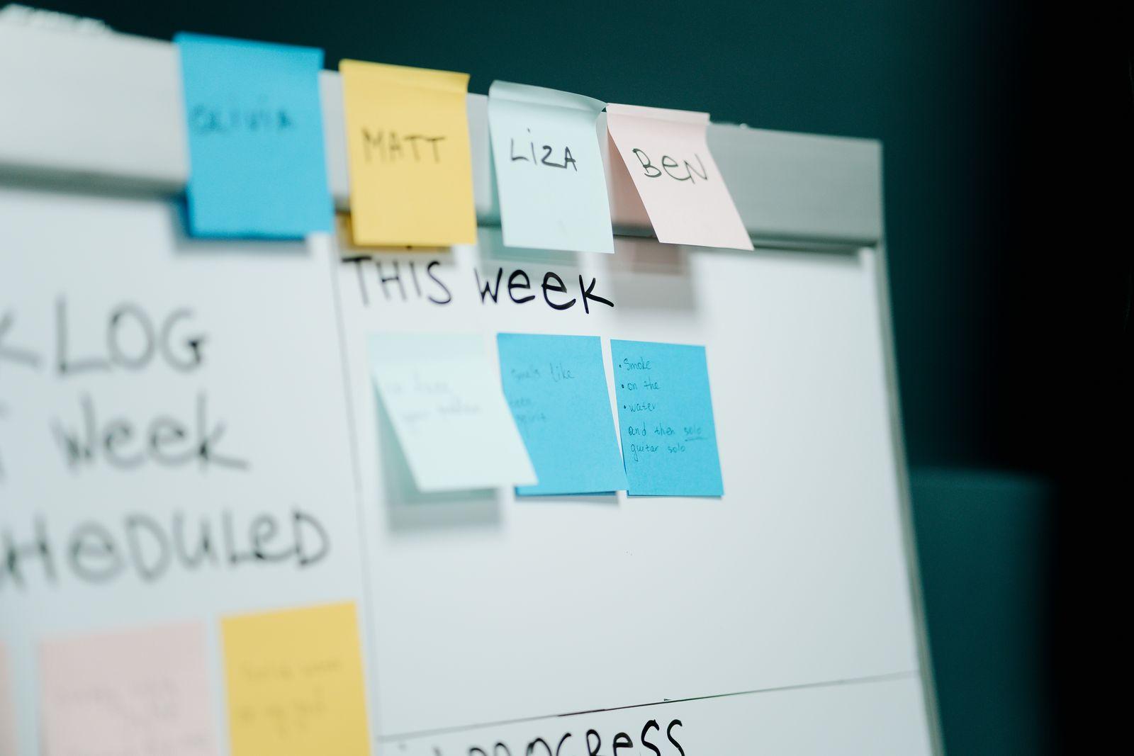 Whiteboard with sticky notes laid out as a weekly schedule