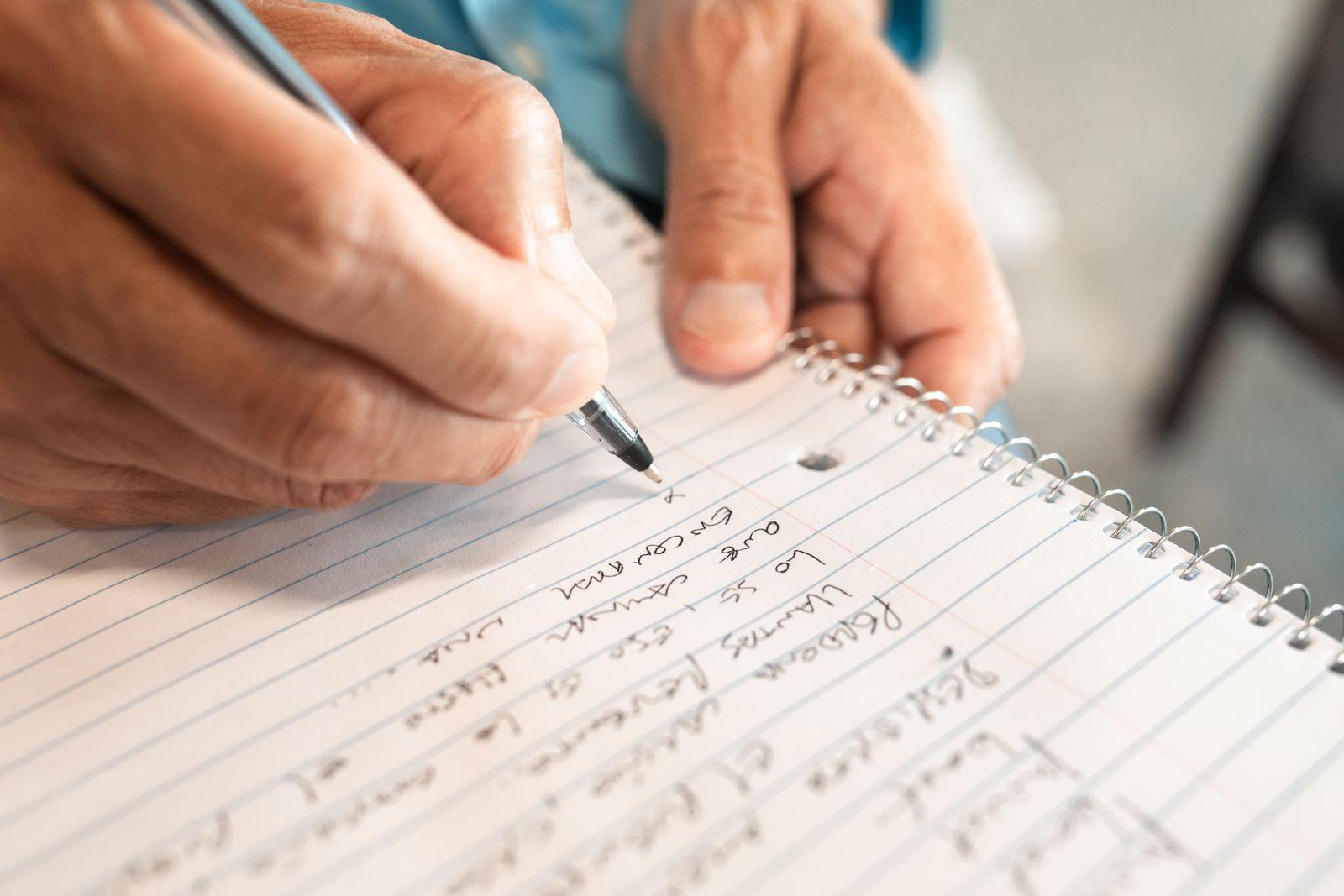 Hand writing a list in a lined spiral notebook