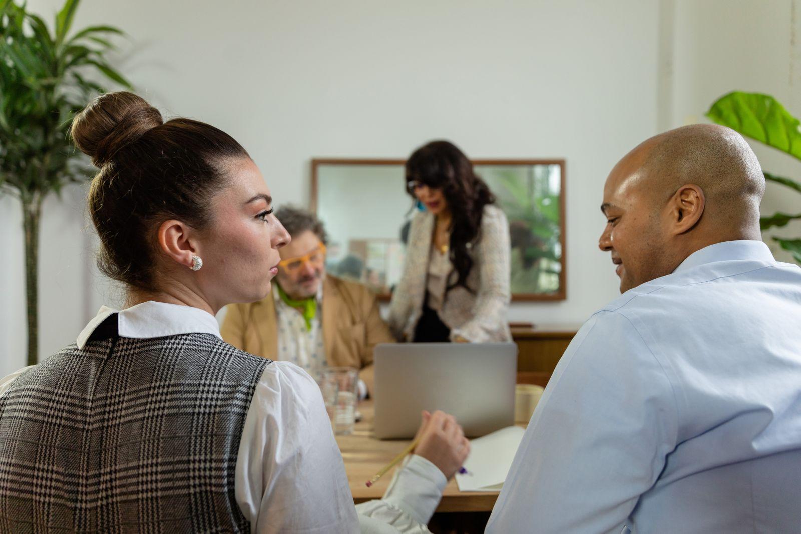 Four colleagues talking around a table with a laptop