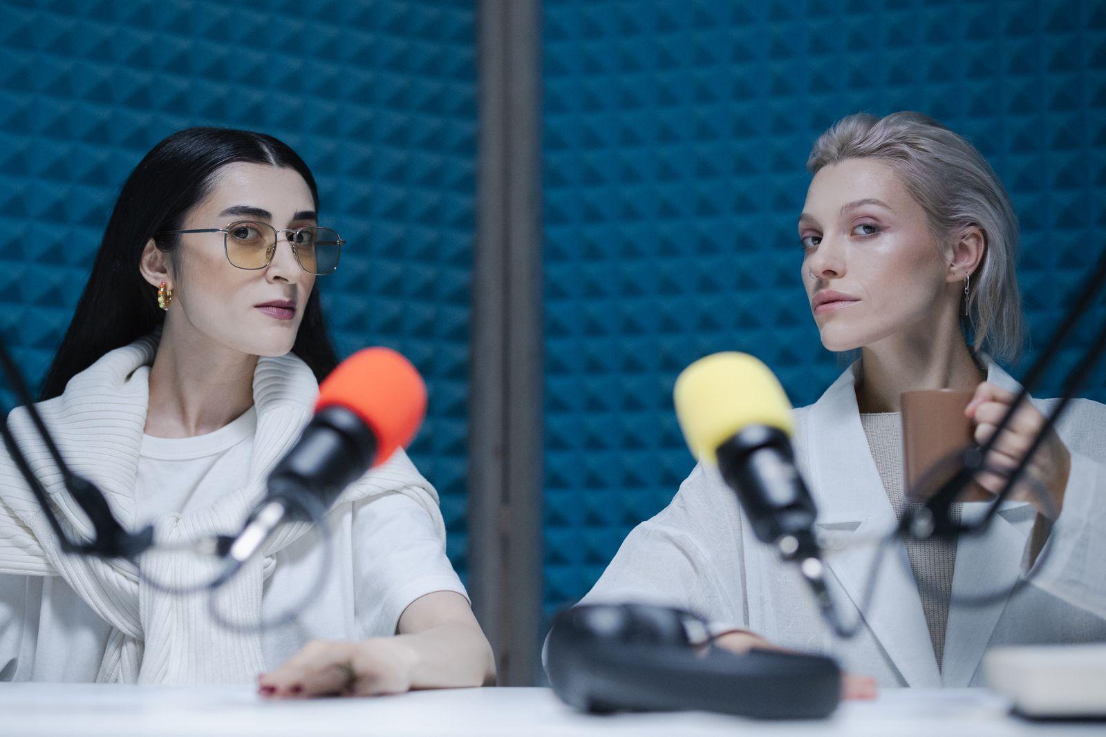 Two podcast hosts at microphones in a soundproofed studio
