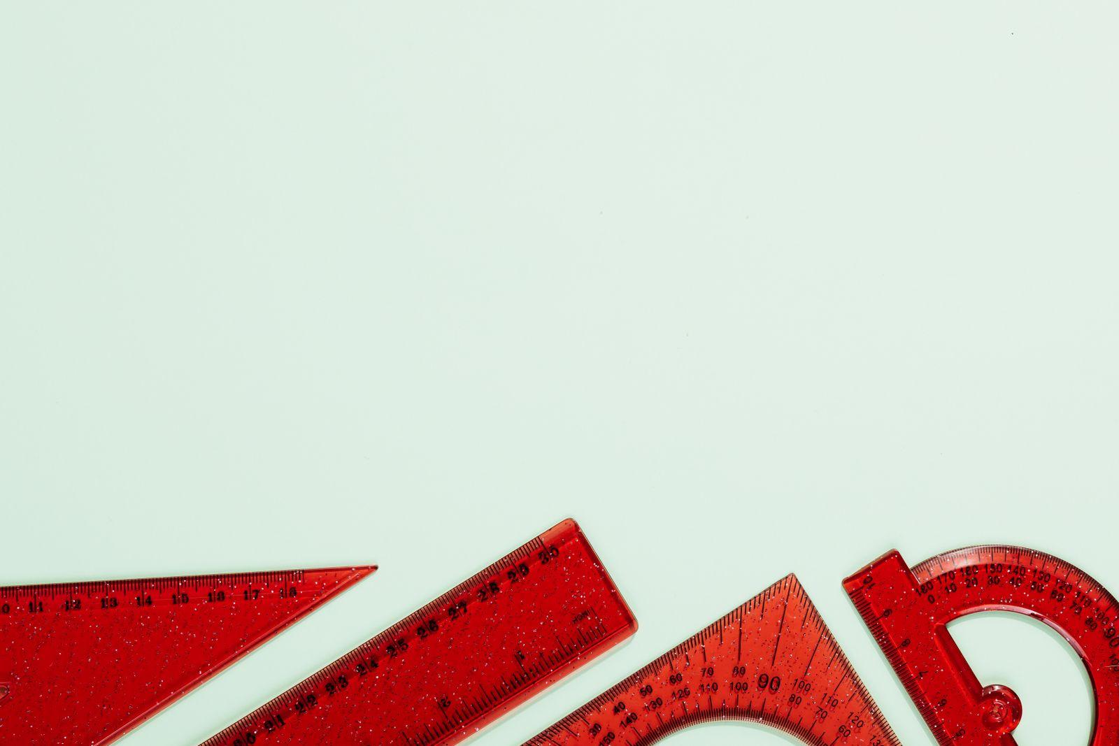 Red rulers and a protractor on a pale green background