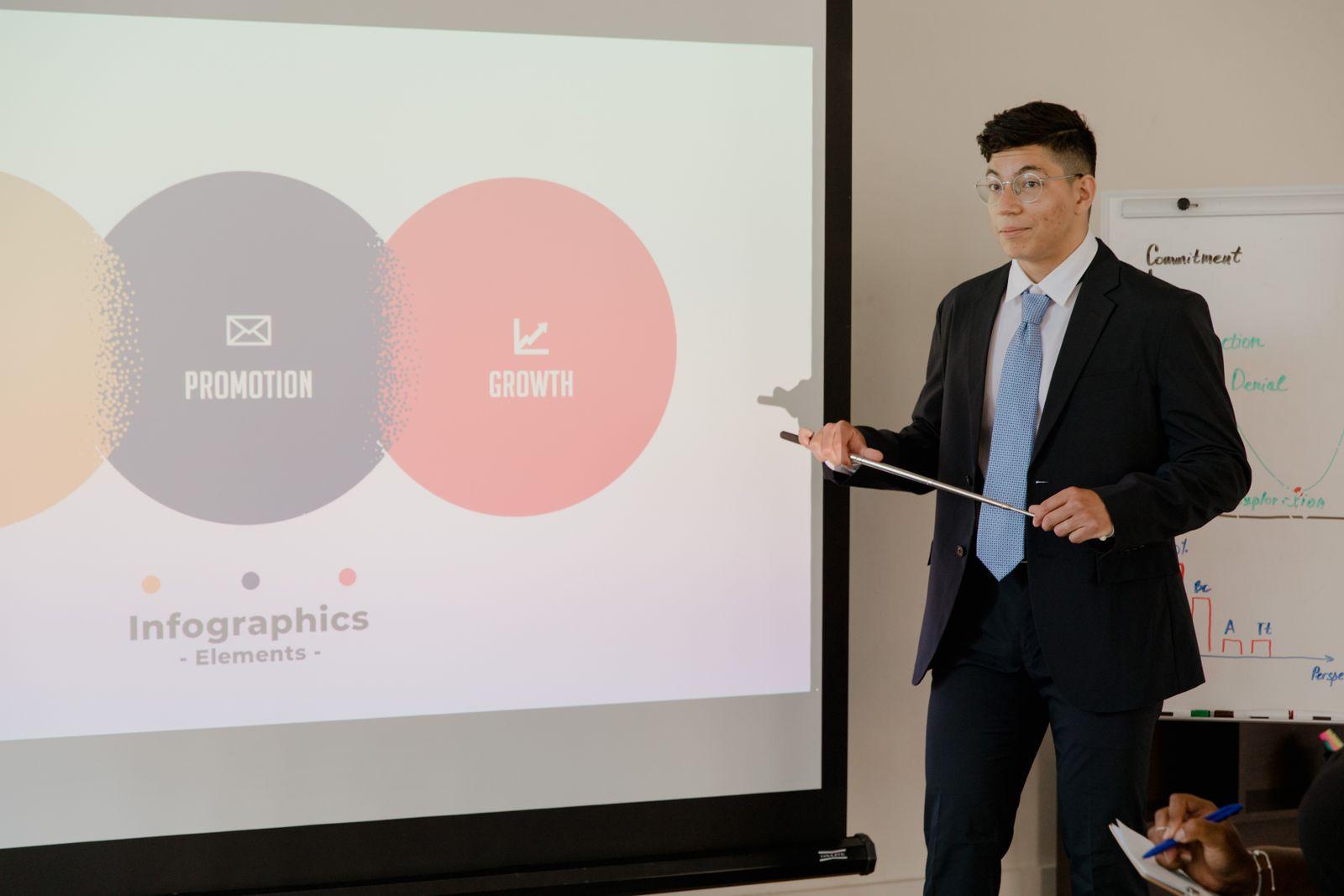 Presenter pointing at slides on a projector screen
