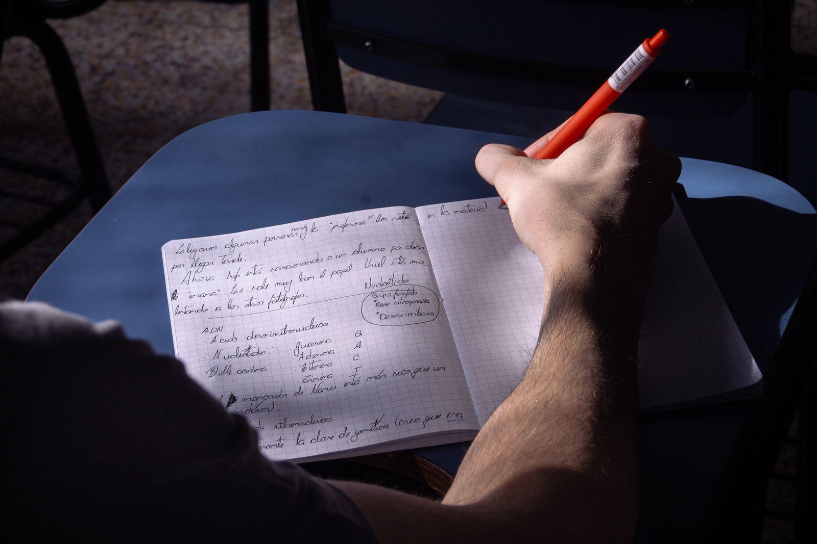 Hand writing notes in a notebook with an orange pen