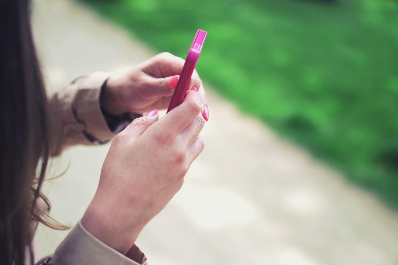 Hands holding a phone with a pink case