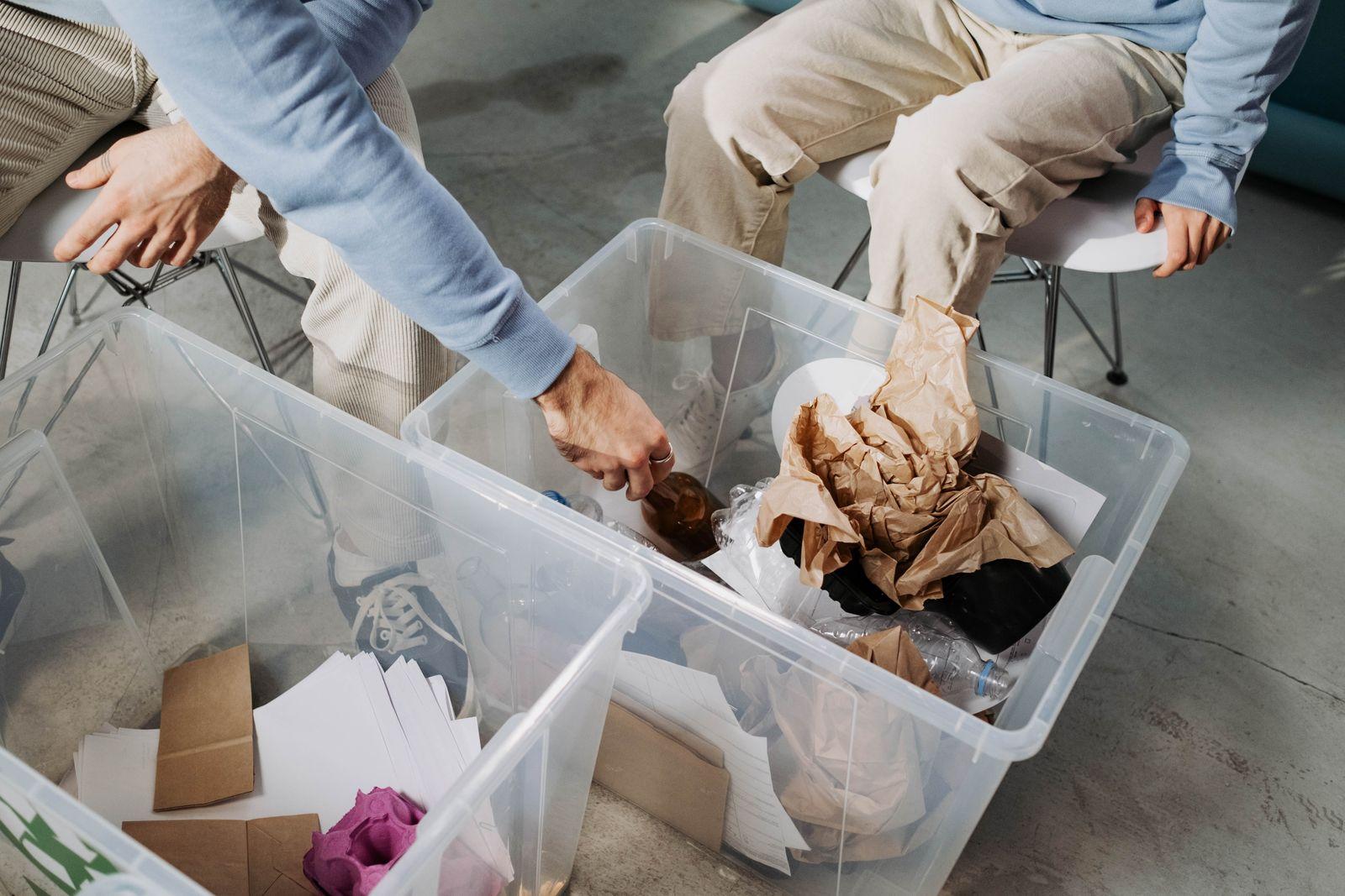 People sorting paper and packaging into clear recycling bins