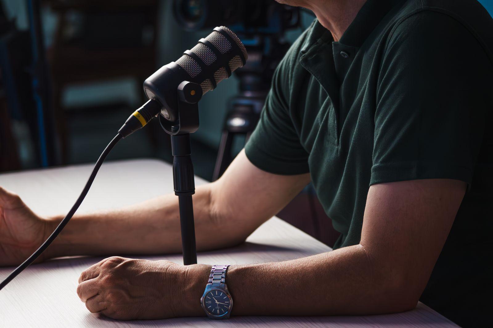 Podcast host sitting at a table in front of a microphone
