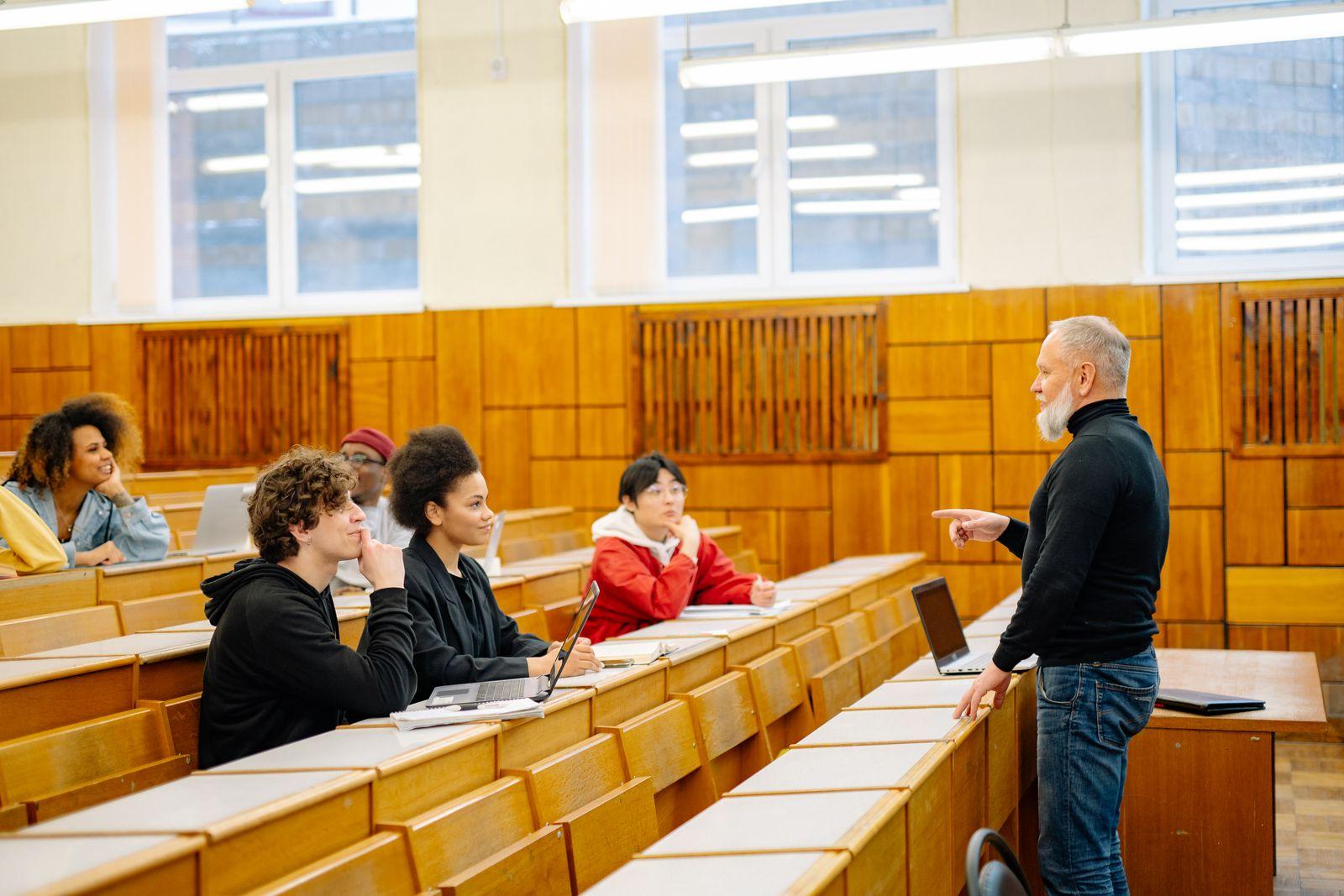 Lecturer talking to students in a wood-panelled lecture hall